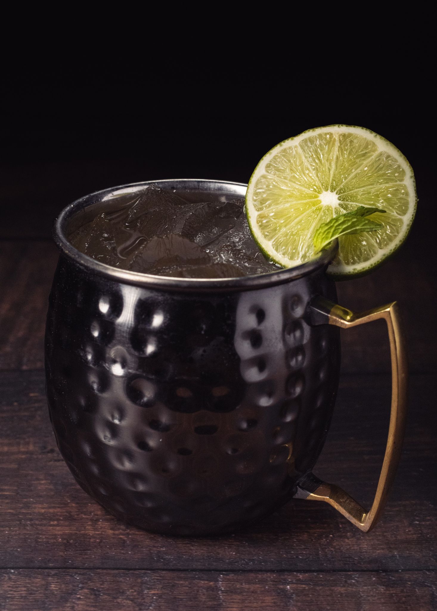 a black mug filled with a drink and a slice of lime