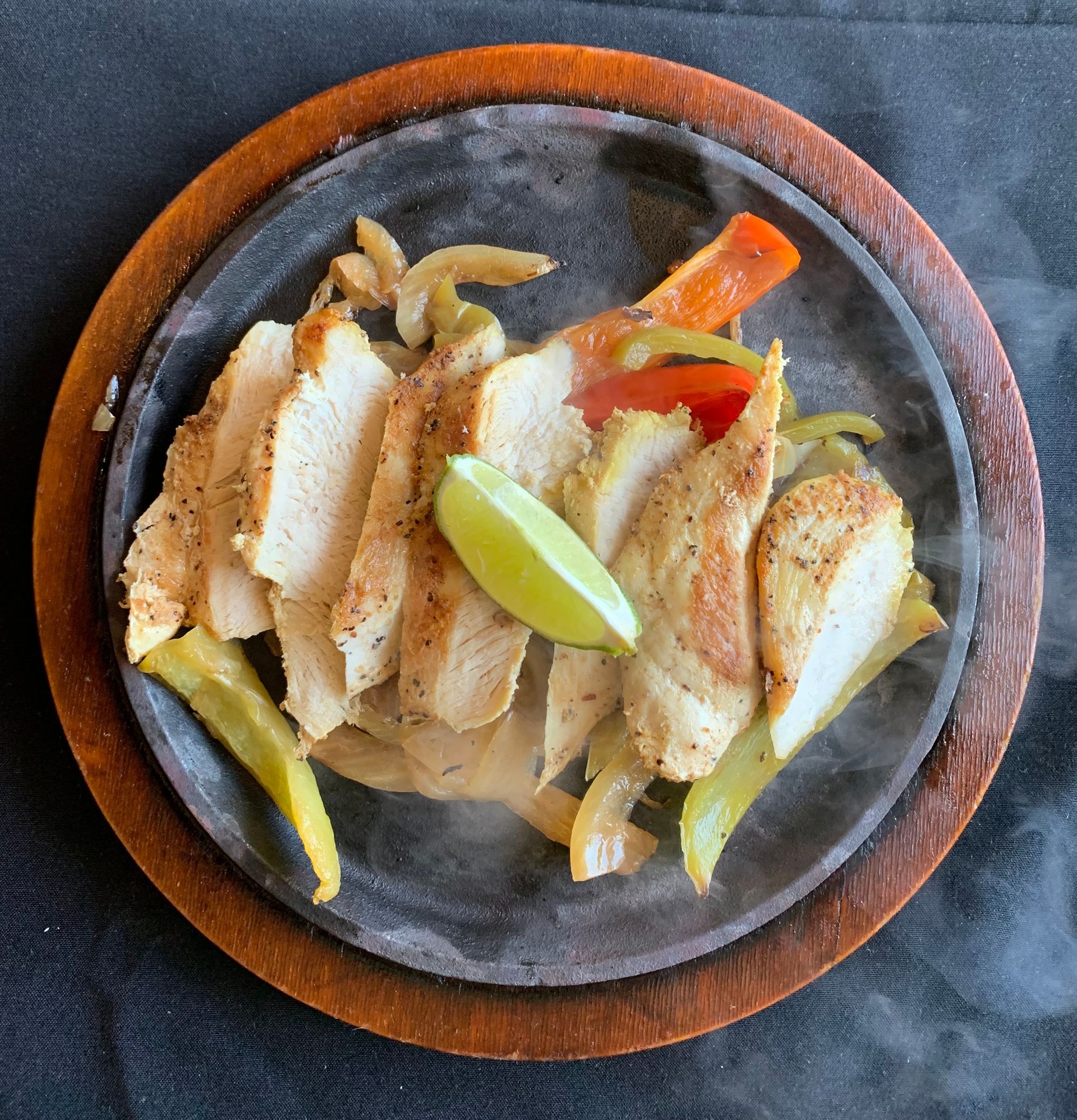 a plate of food with chicken and vegetables on a wooden tray