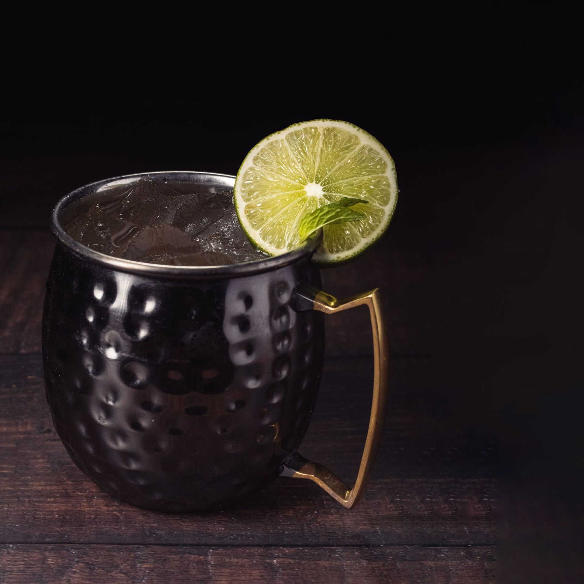 a black mug filled with a drink and a slice of lime