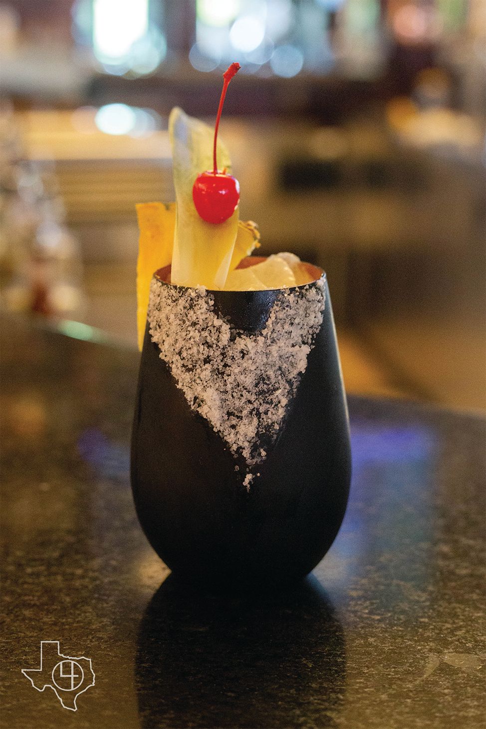 a black glass filled with a drink with a cherry on top