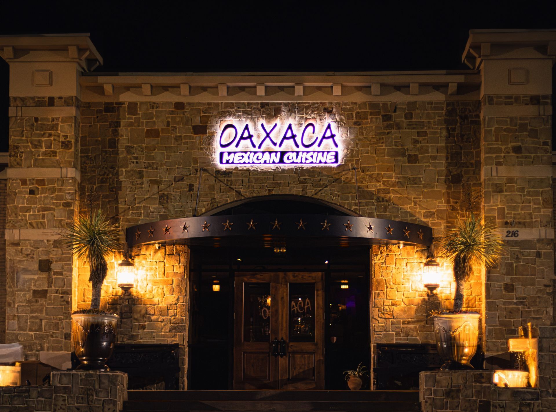 the entrance to Oaxaca restaurant is lit up at night .