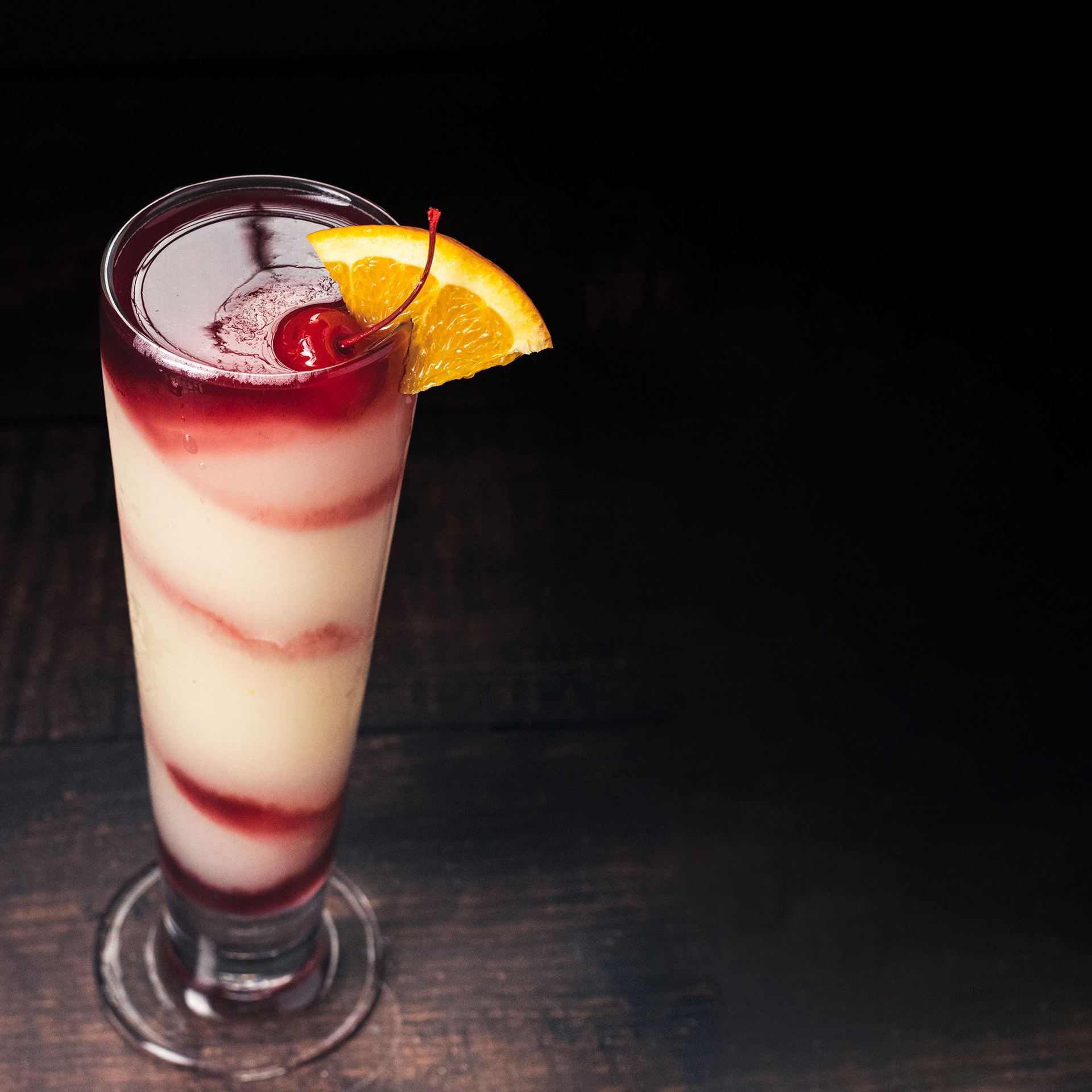 a drink with a cherry and an orange slice on top