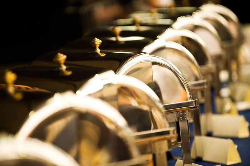 a row of stainless steel buffet containers are lined up on a table