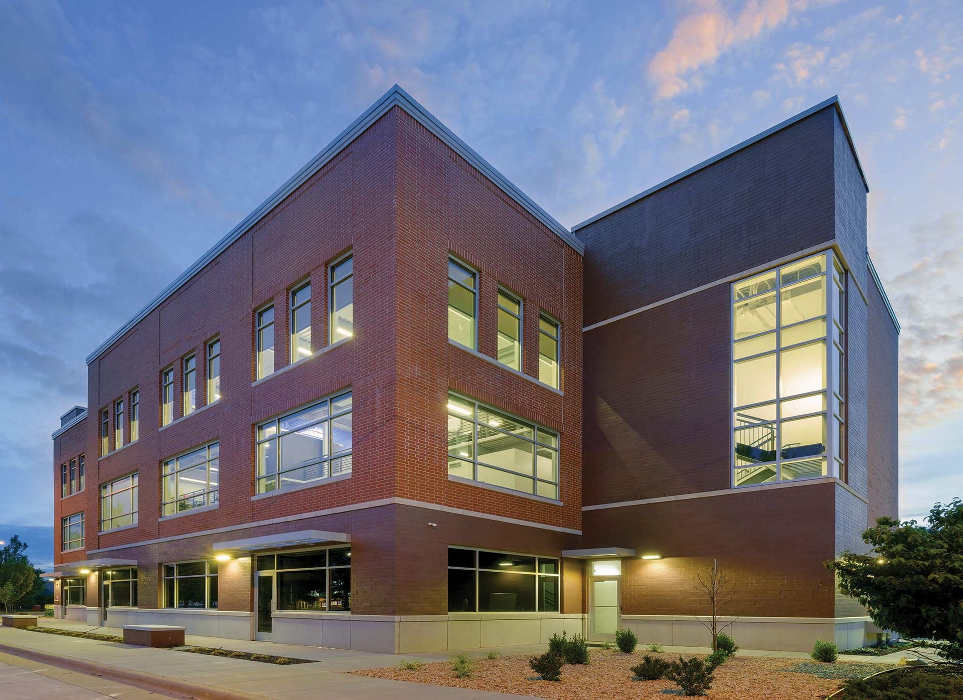 Brick building with large windows, dusk setting.
