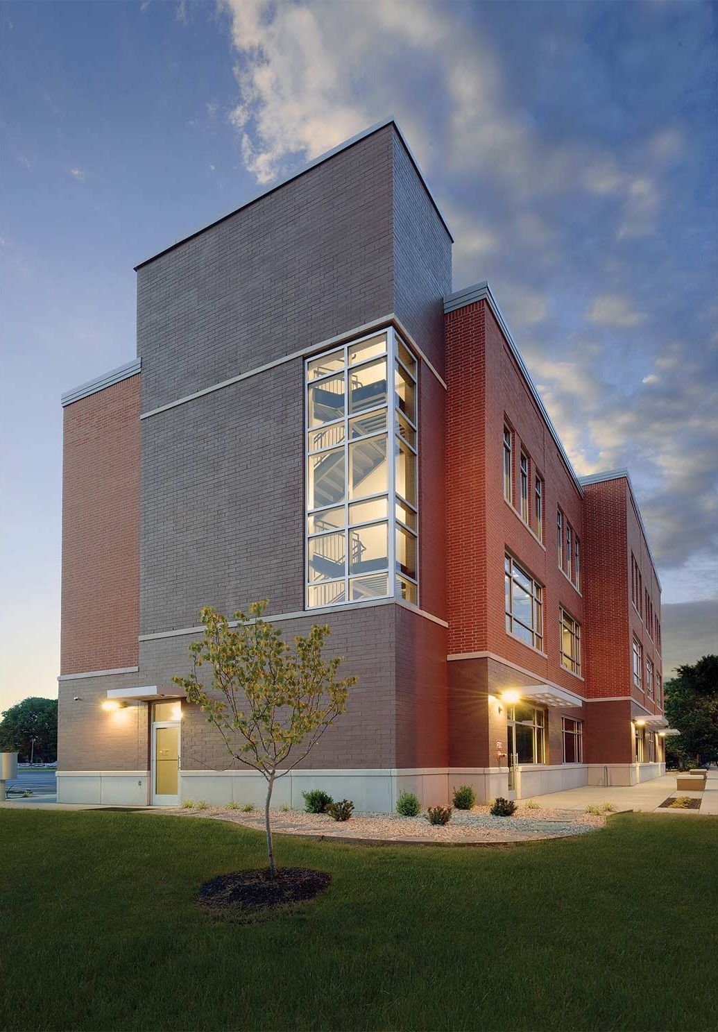 Brick building with large window section, at dusk.
