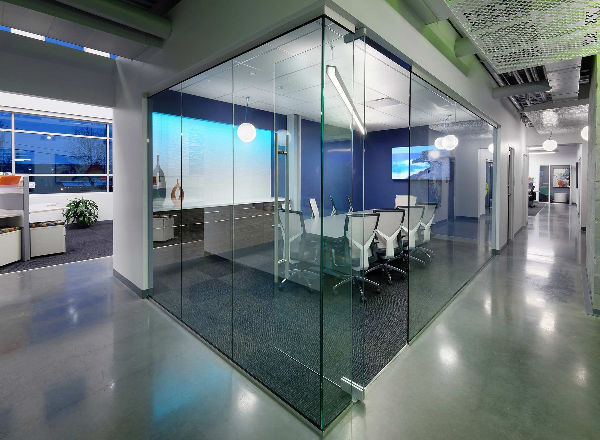 Modern office hallway with glass-walled conference room, white and grey interior with natural lighting.