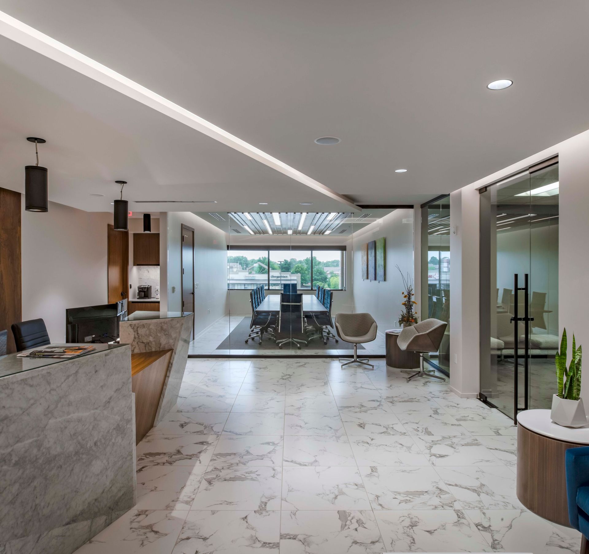 Modern office lobby with marble floors, reception desk, and meeting room in the background.