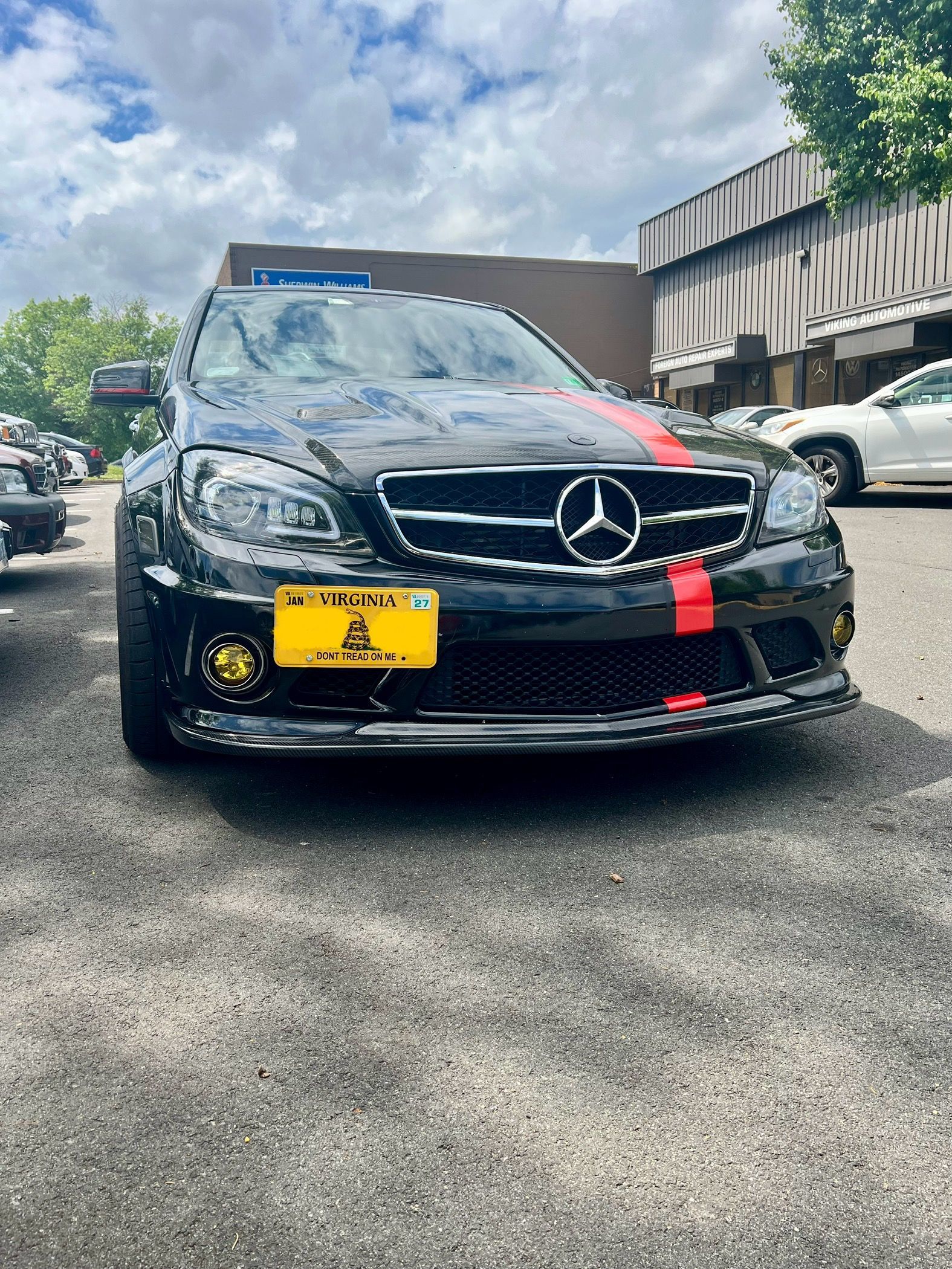 A black mercedes benz is parked in a parking lot.