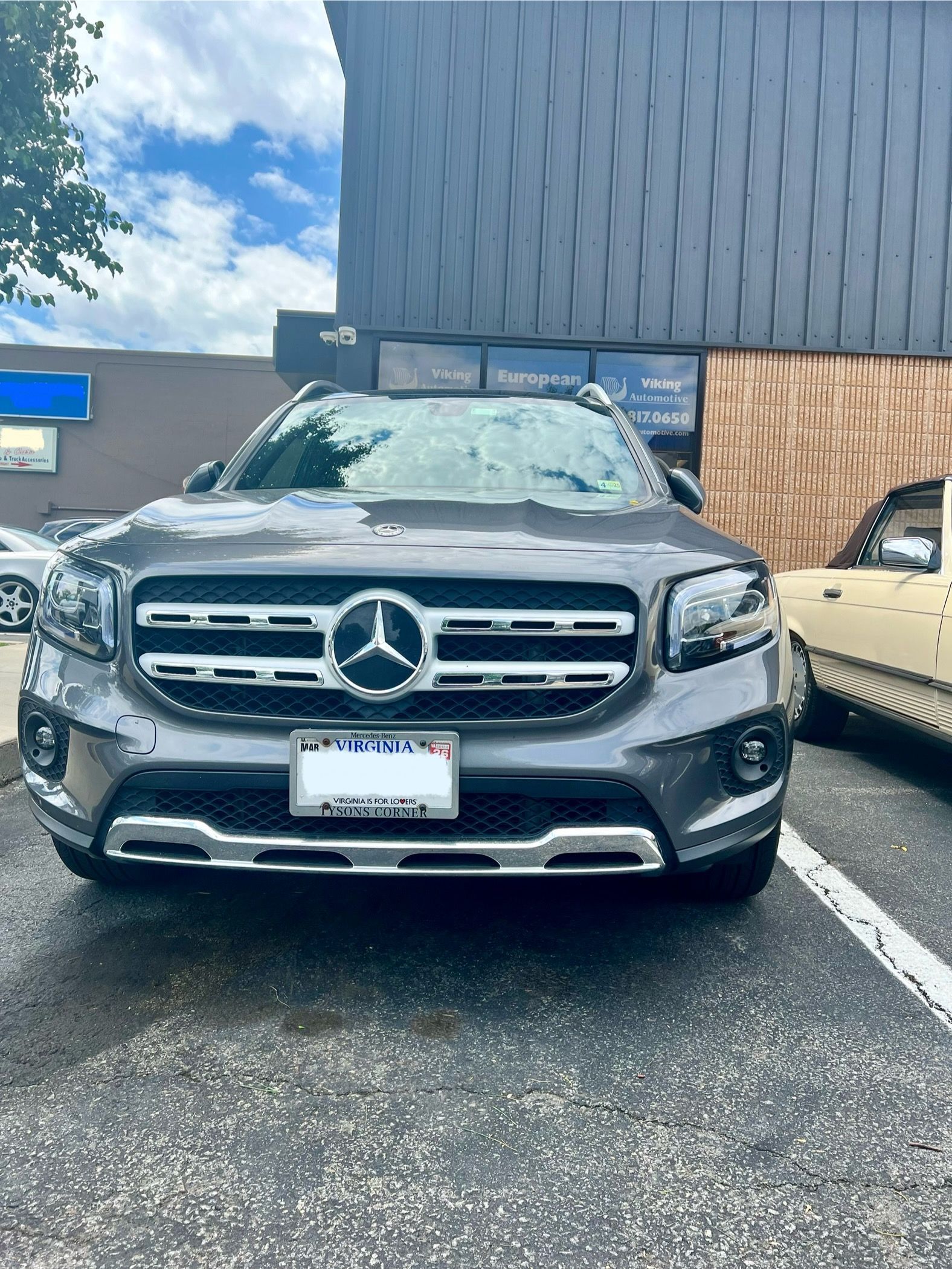A mercedes benz glb is parked in a parking lot in front of a building.