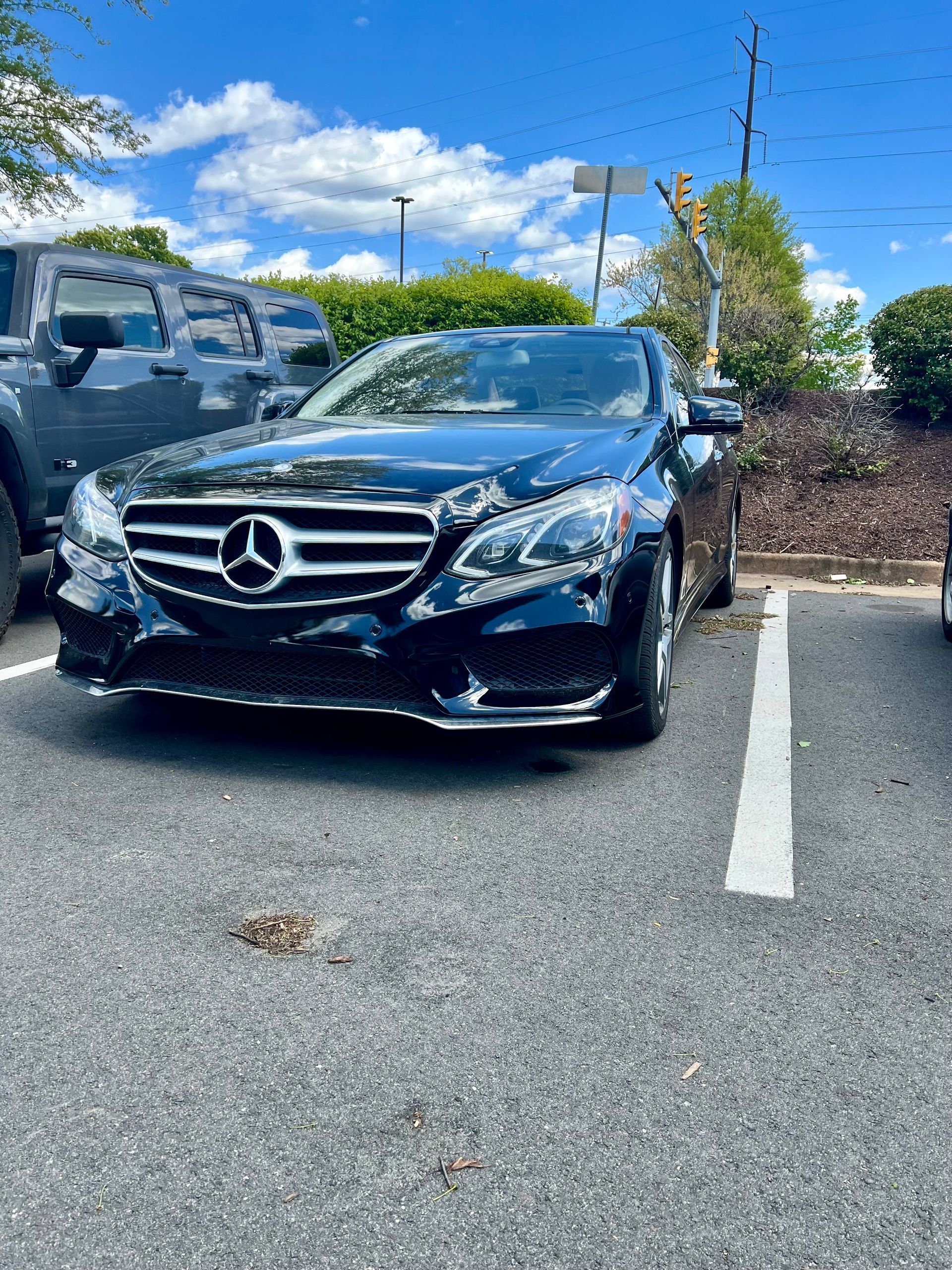 A black mercedes benz is parked in a parking lot.