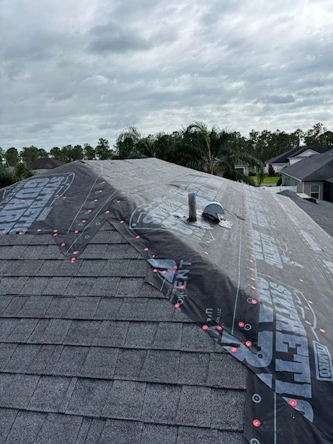 A partially installed shingle roof with black synthetic underlayment visible over the bare wood decking.