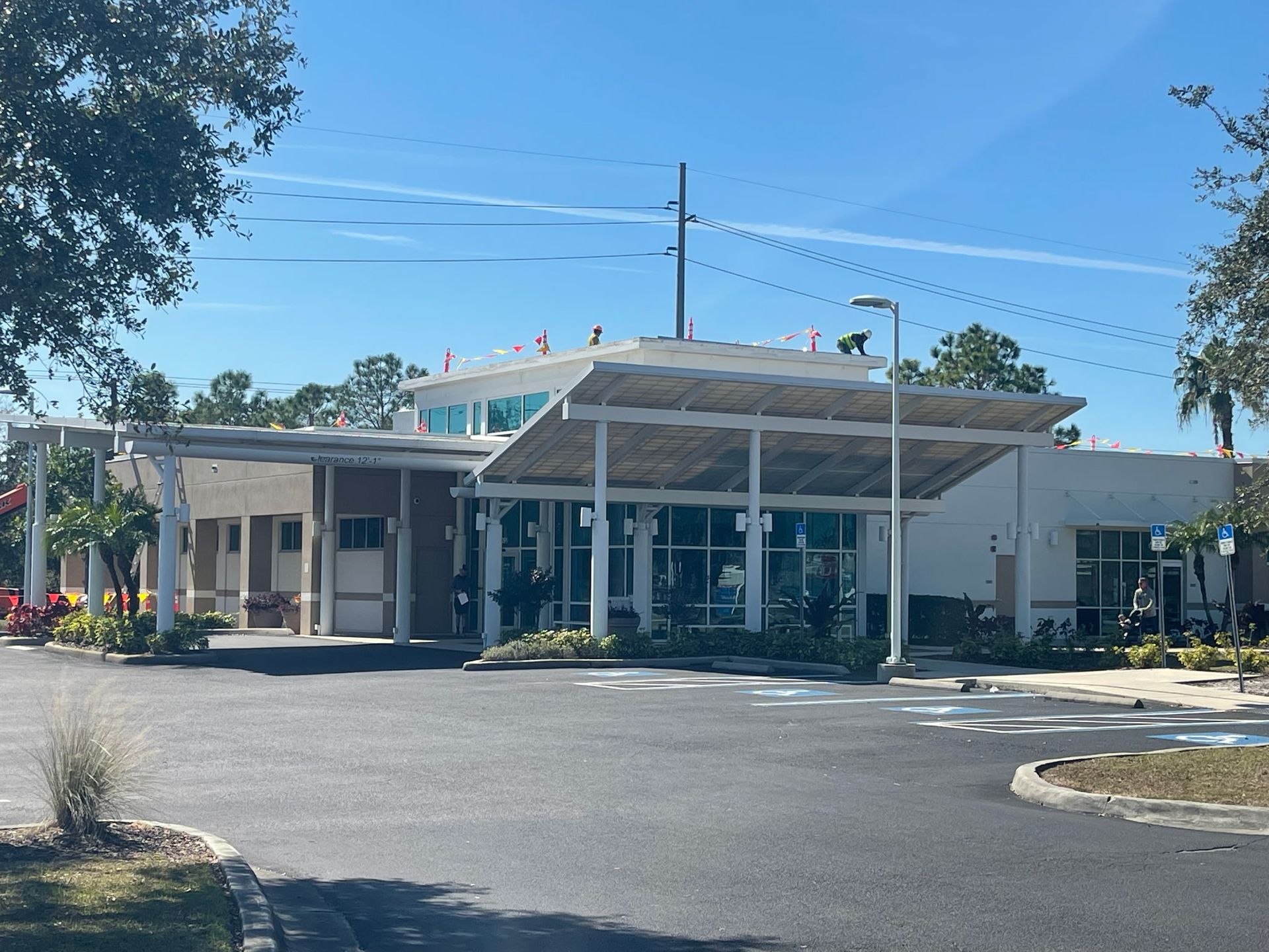 Building with a canopy, large windows, and a paved parking lot on a sunny day.