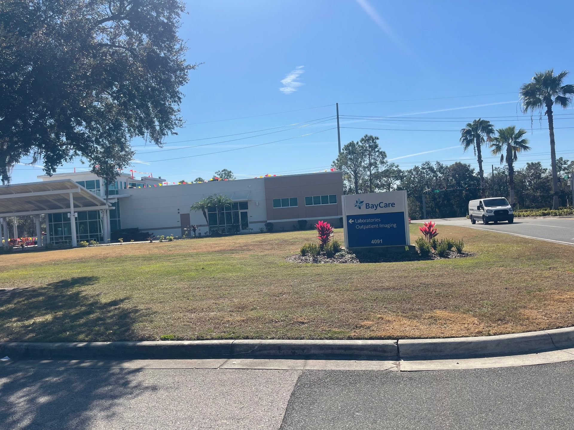 BayCare sign in front of a low building with trees and a blue sky.