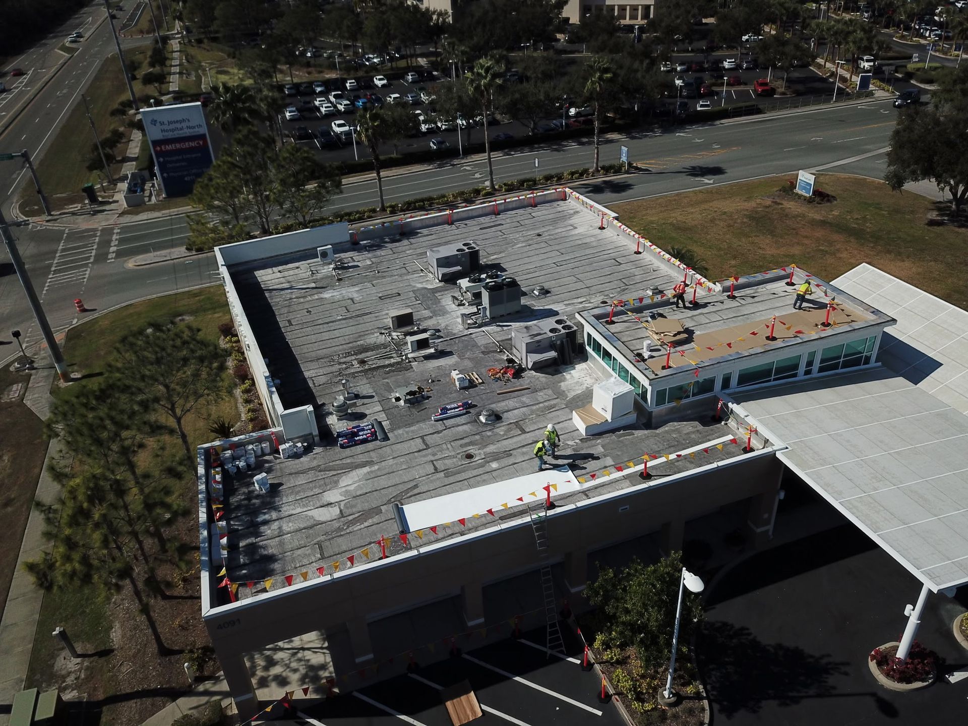 Aerial view of a building roof under construction with workers and safety cones.