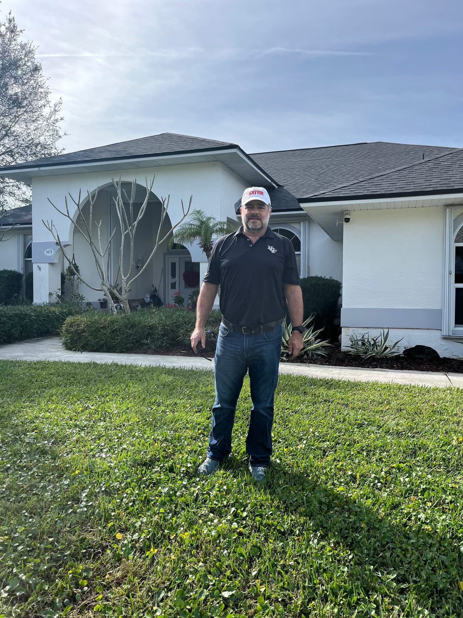 Man standing in front of a white house with a dark roof.