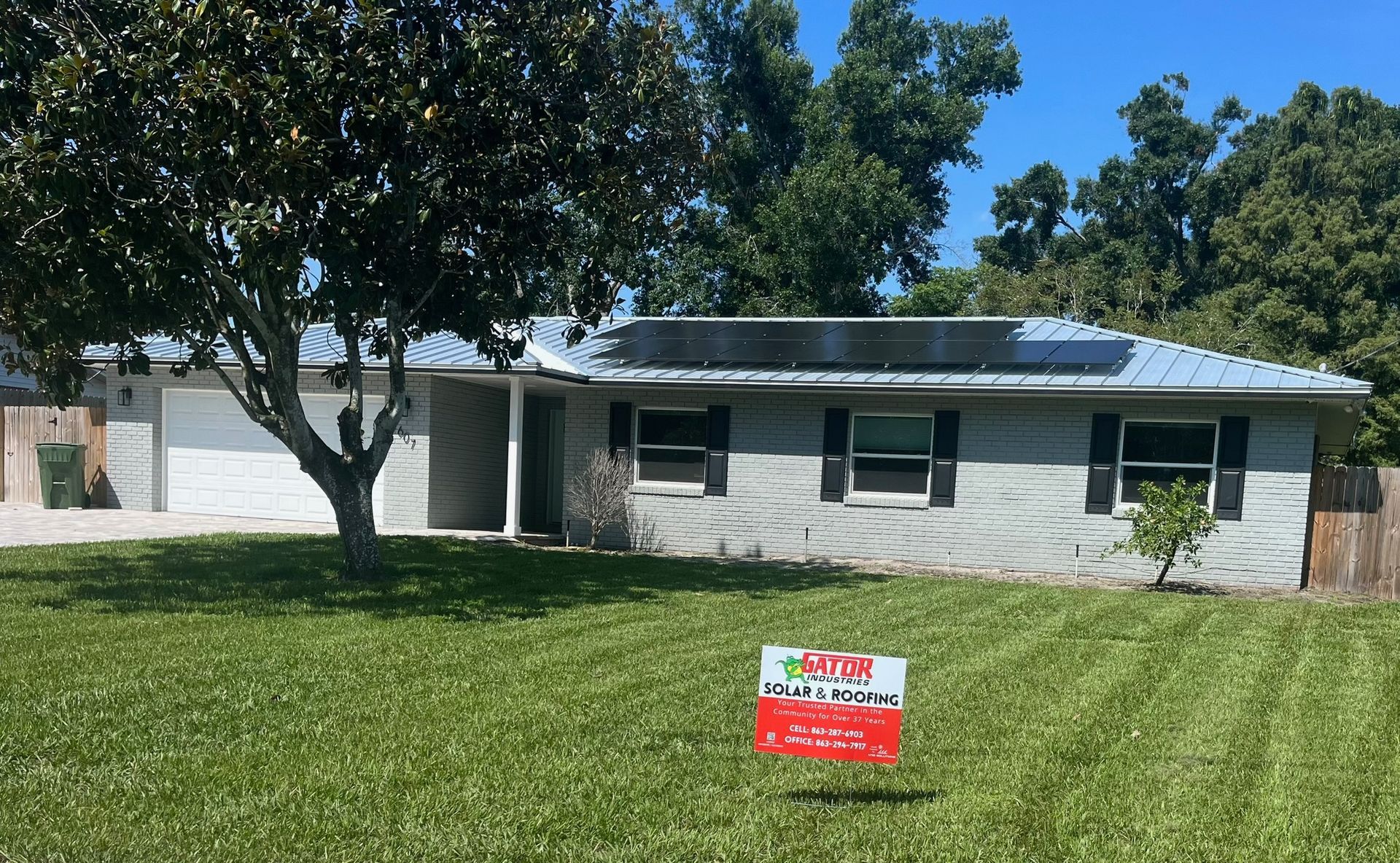 House with gray brick exterior, metal roof, solar panels, and a 