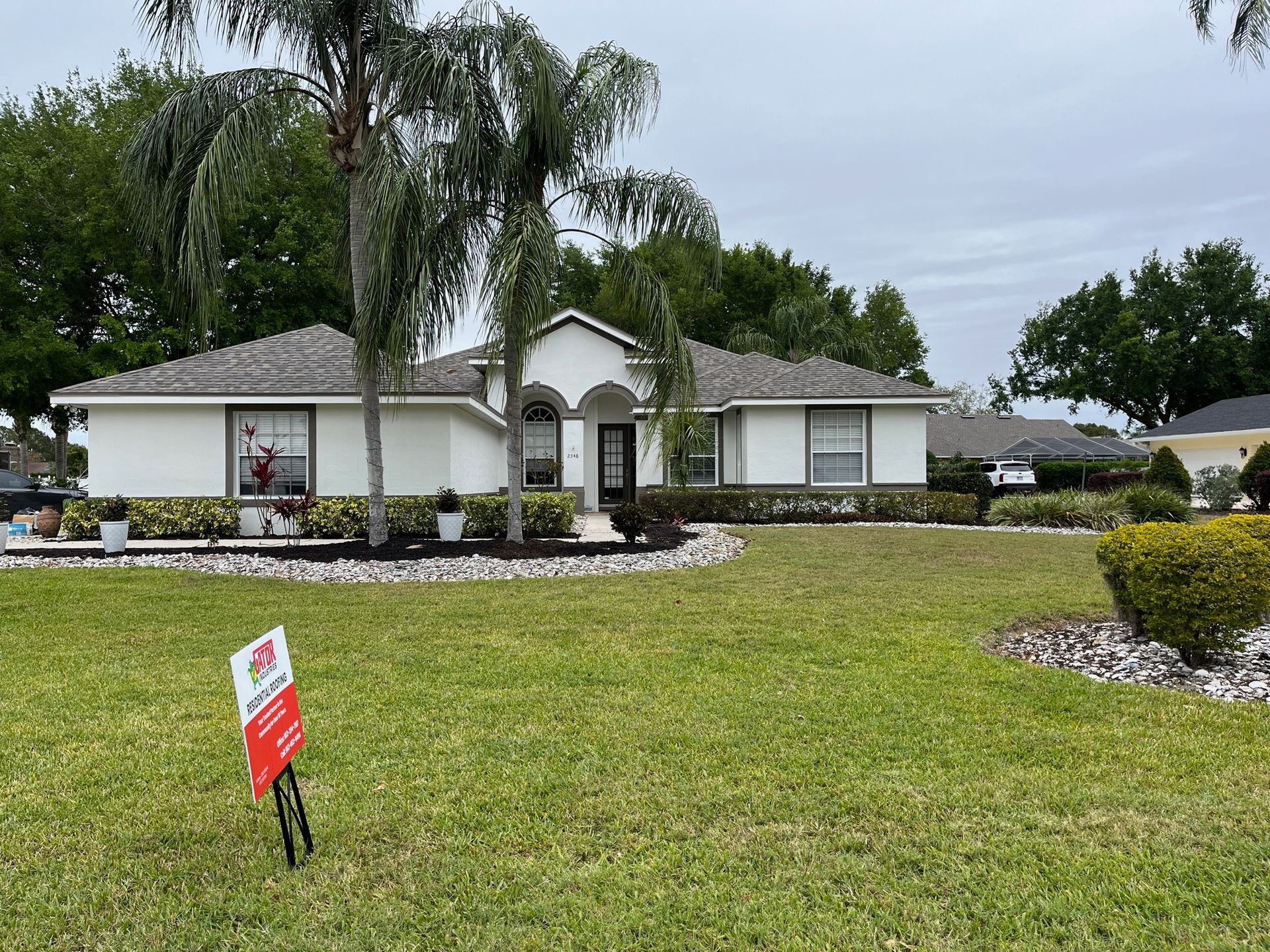 A white house with a dark roof and manicured lawn. A 