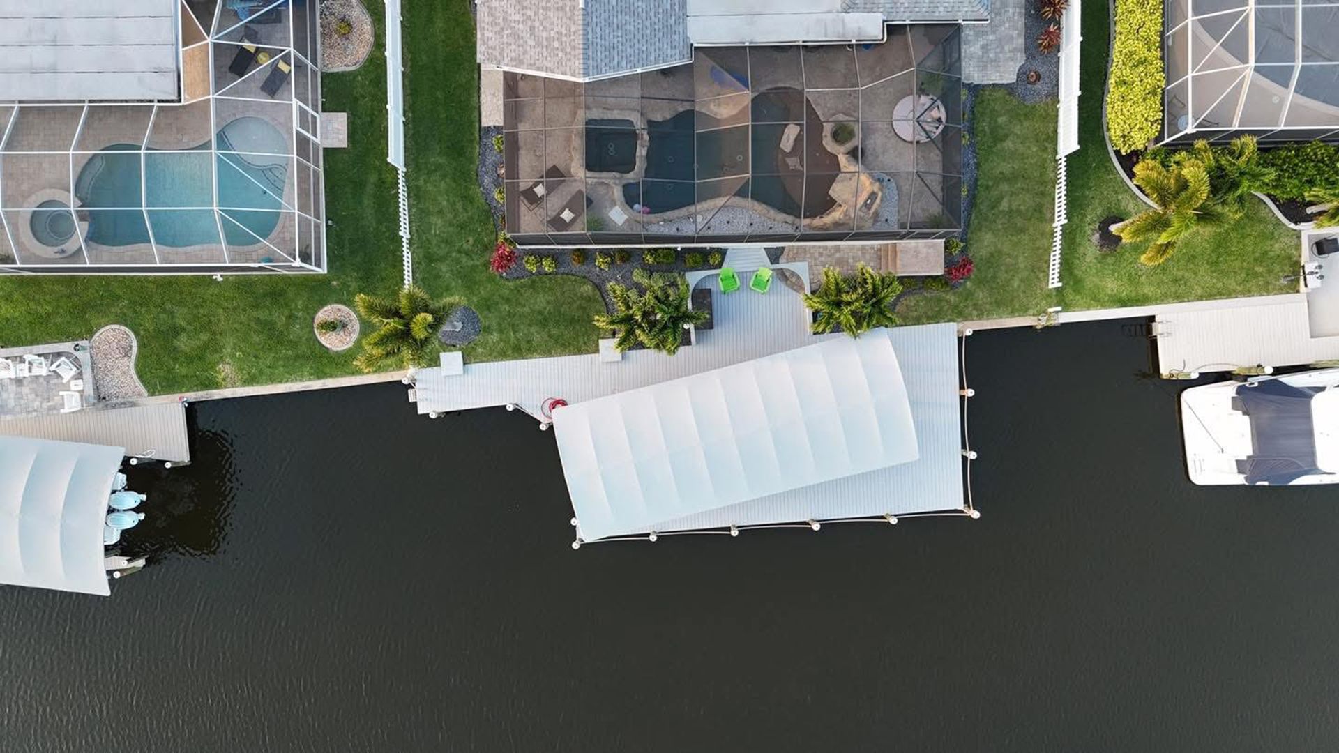 Aerial view of a waterfront property with docks, boats, and a backyard pool.