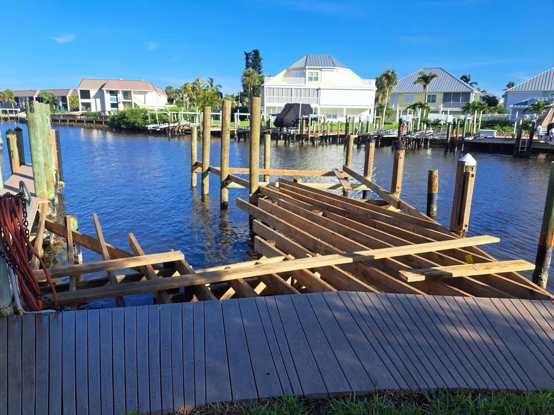 Wooden dock by a calm canal with waterfront homes under a bright blue sky