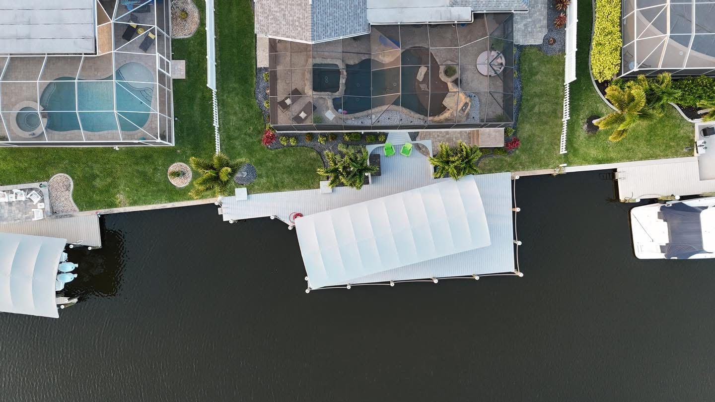 Aerial view of waterfront homes with docks and a boat on dark water