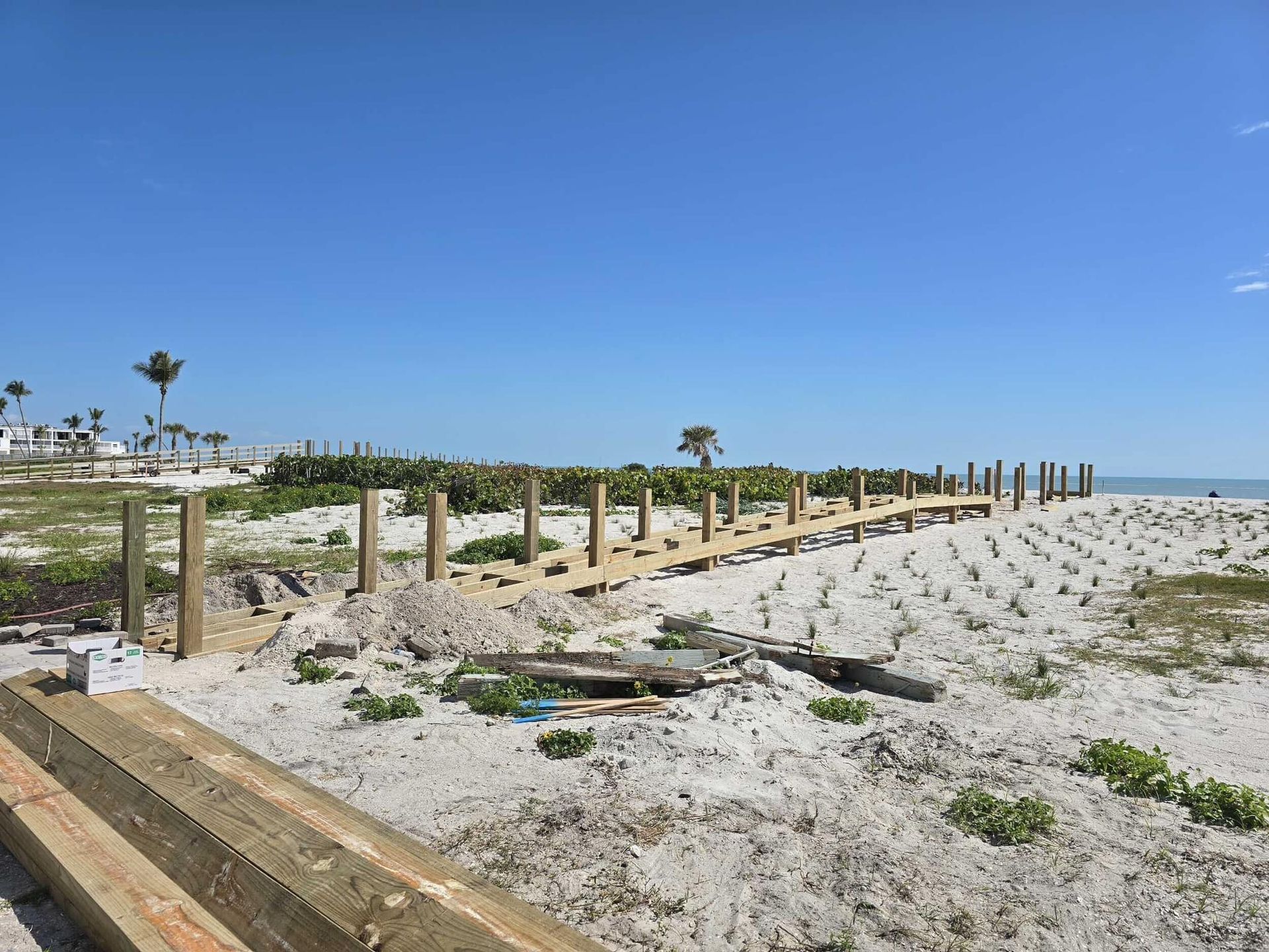 Sandy beach with weathered wooden fence posts under a clear blue sky