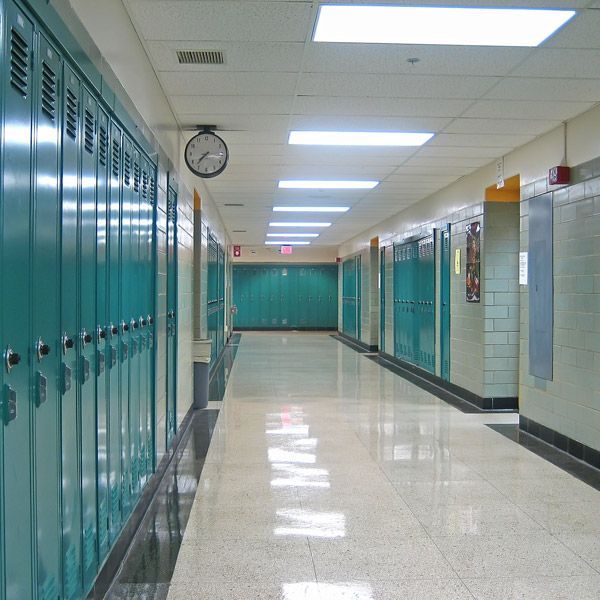 A long hallway with blue lockers and a clock on the wall