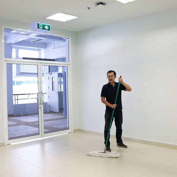 A man is mopping the floor in an empty corridor