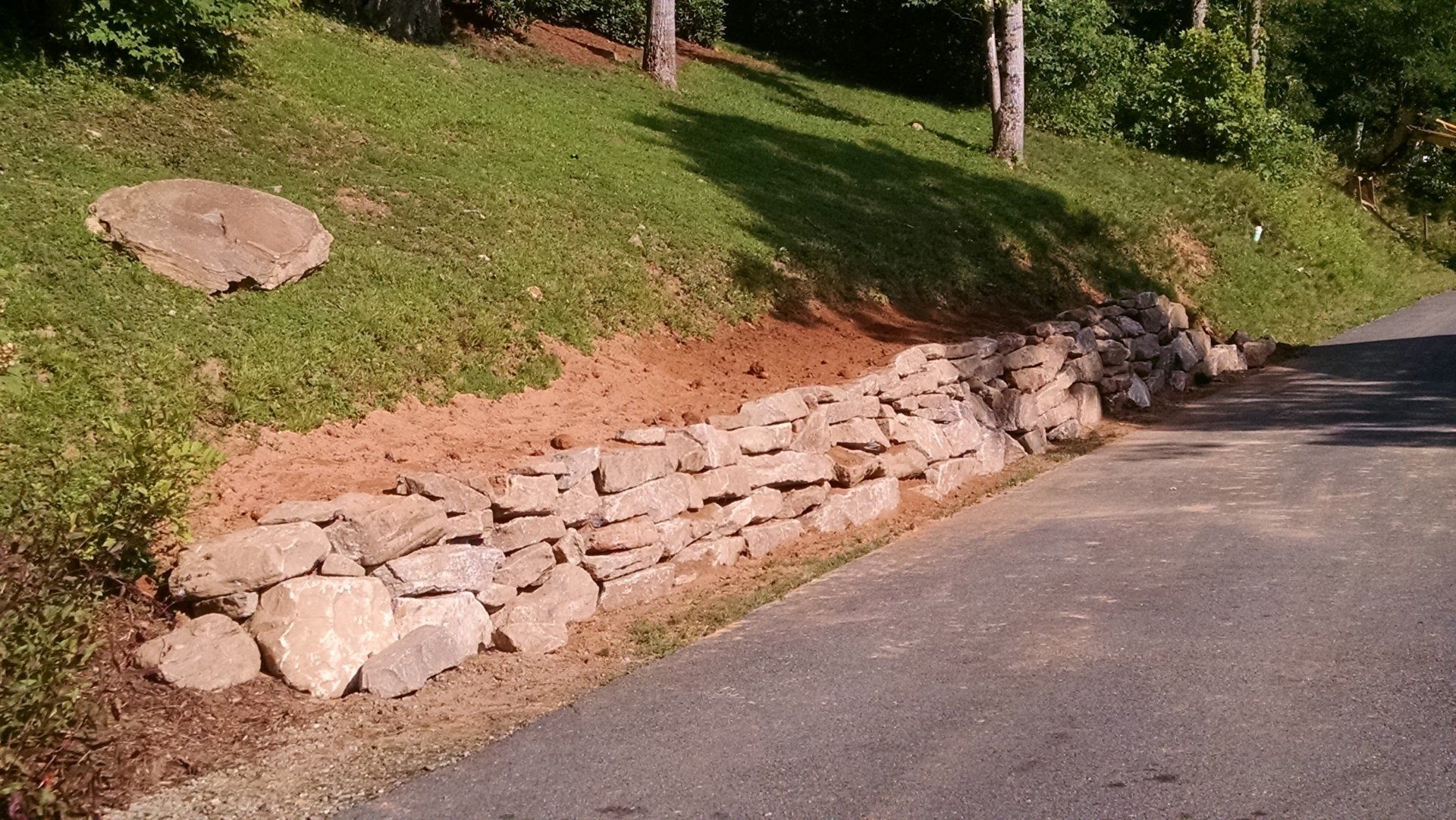 Beginning start to a boulder wall, with landscaping.