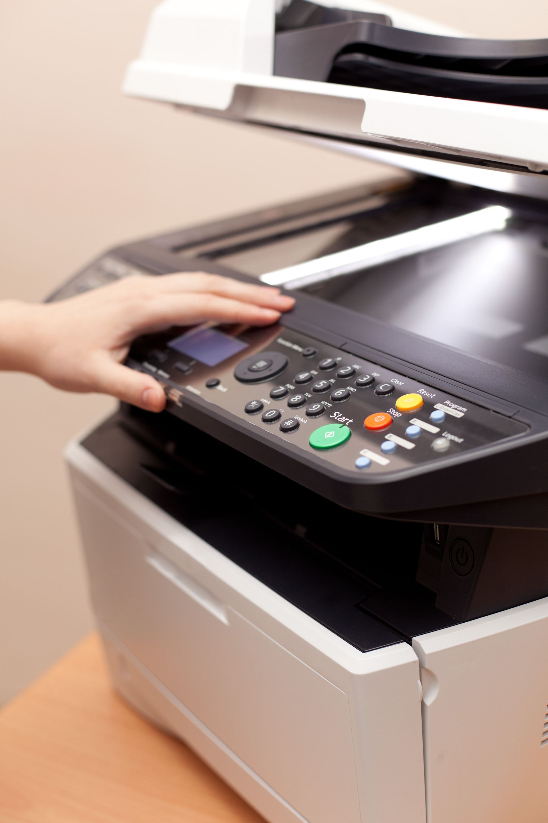 Hand on printer control panel, preparing to copy.
