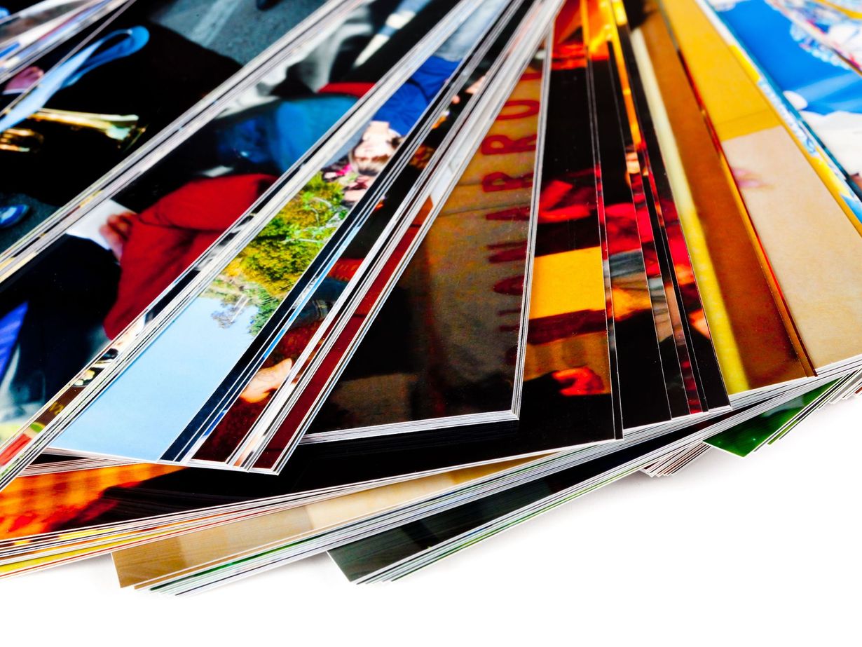 Close-up of a fan of printed photographs with colorful images visible.