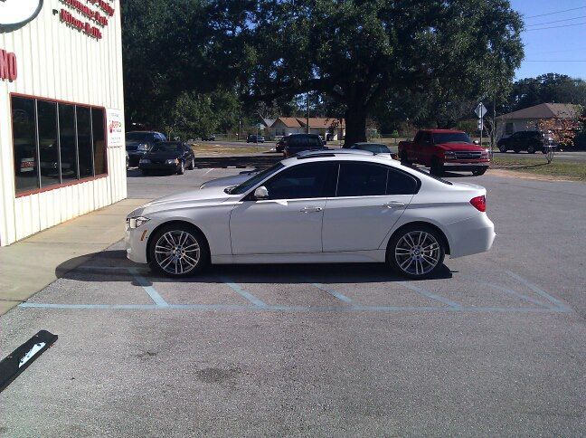 a white car is parked in a parking lot in front of a building
