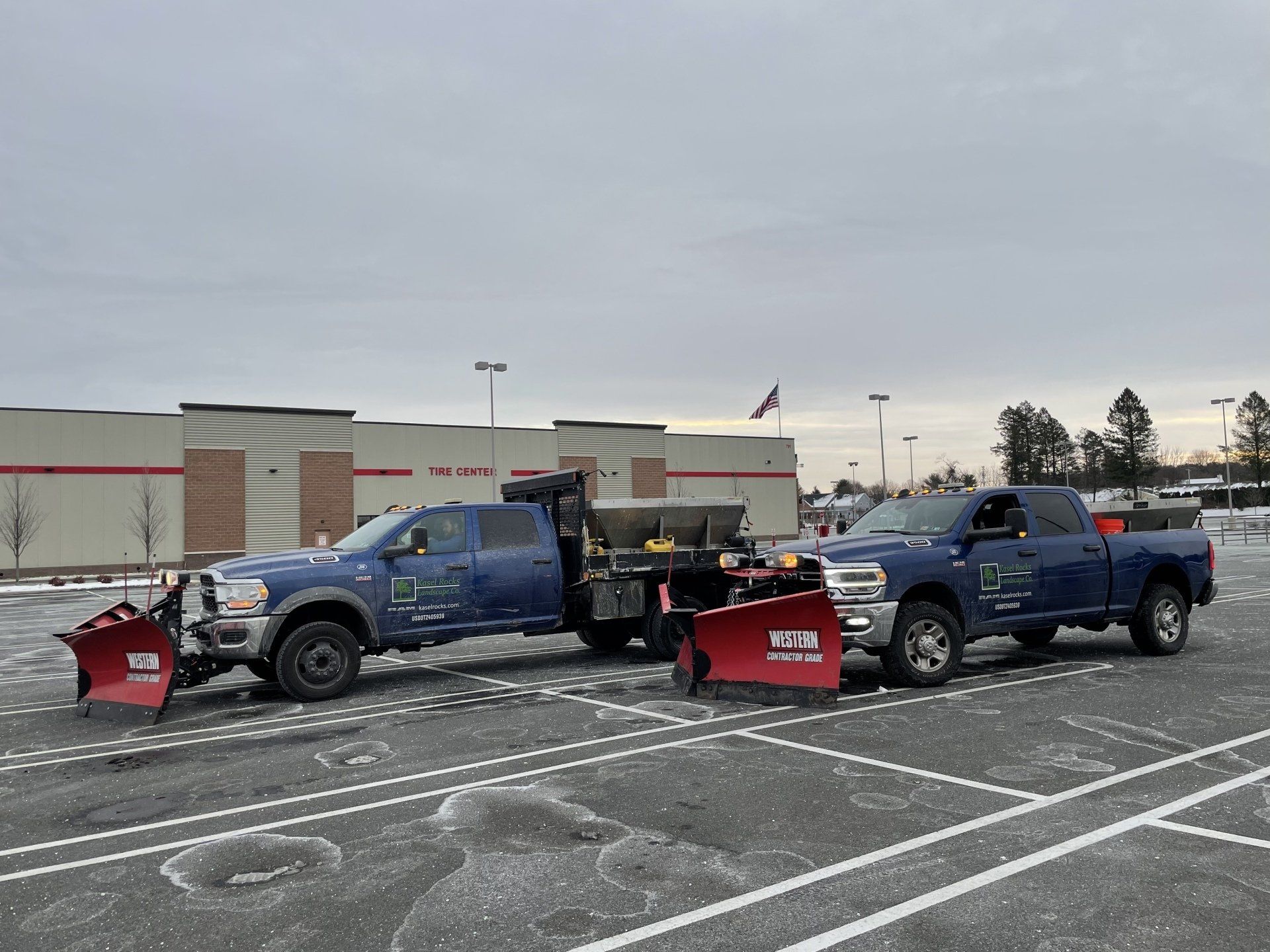 Two snow plows are parked next to each other in a parking lot