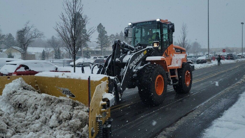 A tractor is plowing snow on the side of the road