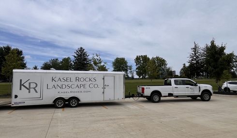 A truck is pulling a trailer that says kr landscape co. on it.