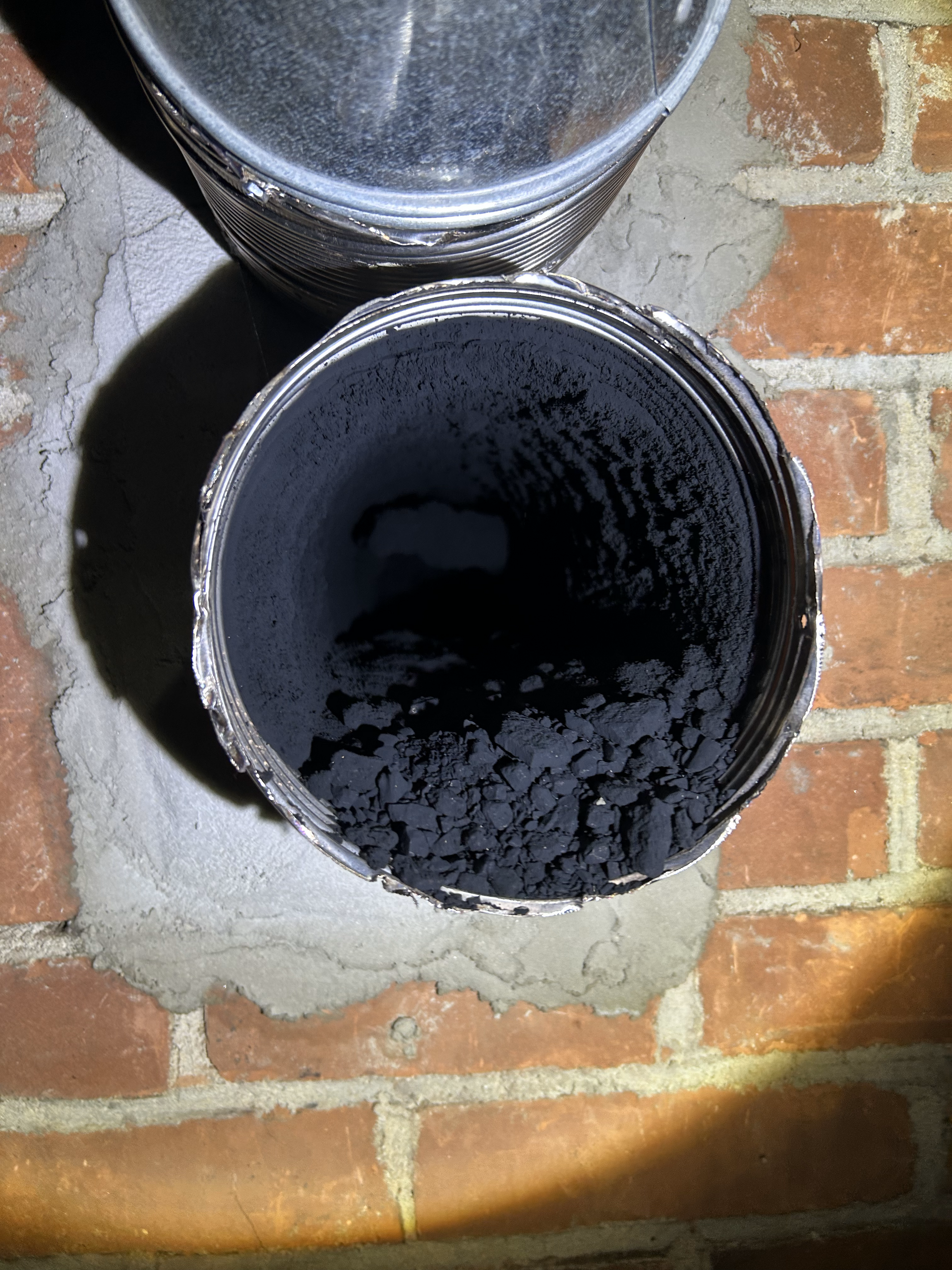 A close up of a dirty pipe on a brick wall.