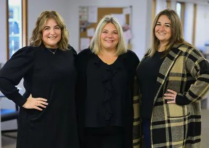 Three women are posing for a picture together in a room.