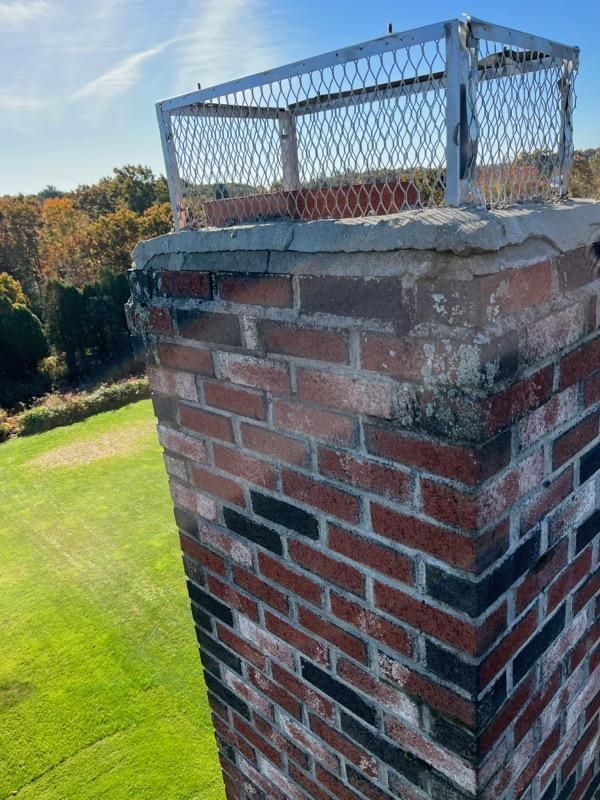 A brick chimney with a metal cage on top of it.
