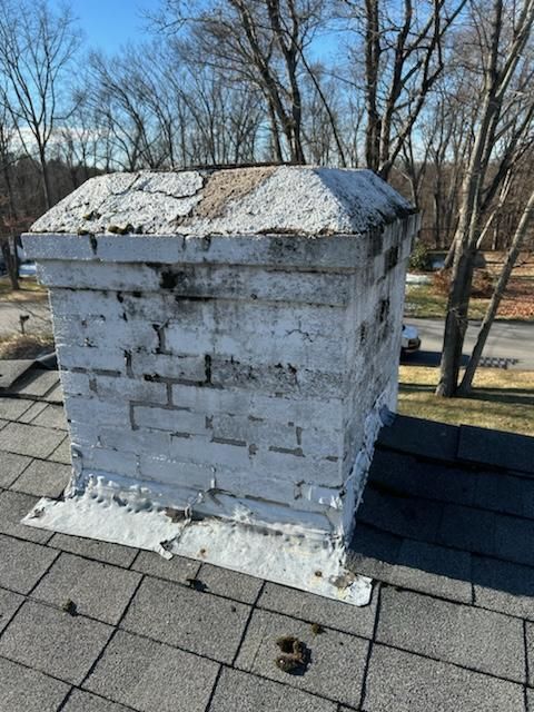A white brick chimney is sitting on top of a roof.