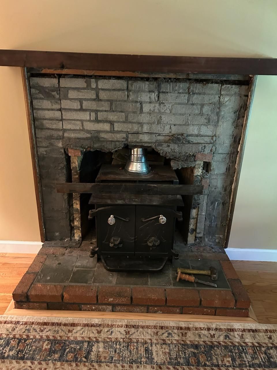 A wood stove is sitting in a brick fireplace.