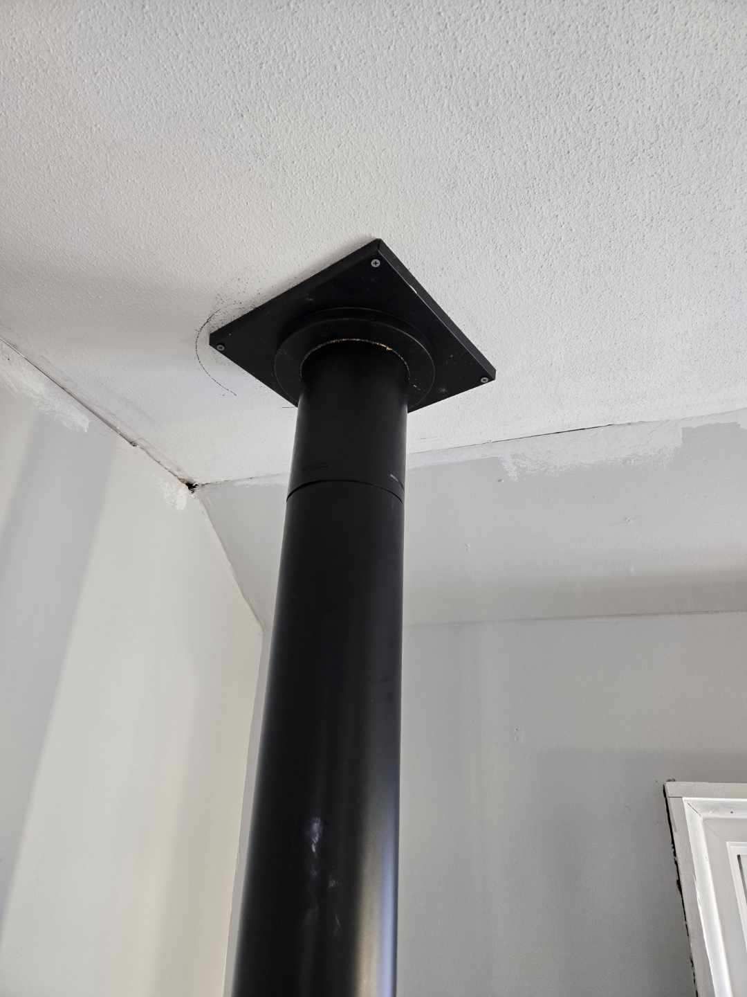 A black pipe is hanging from the ceiling of a room.