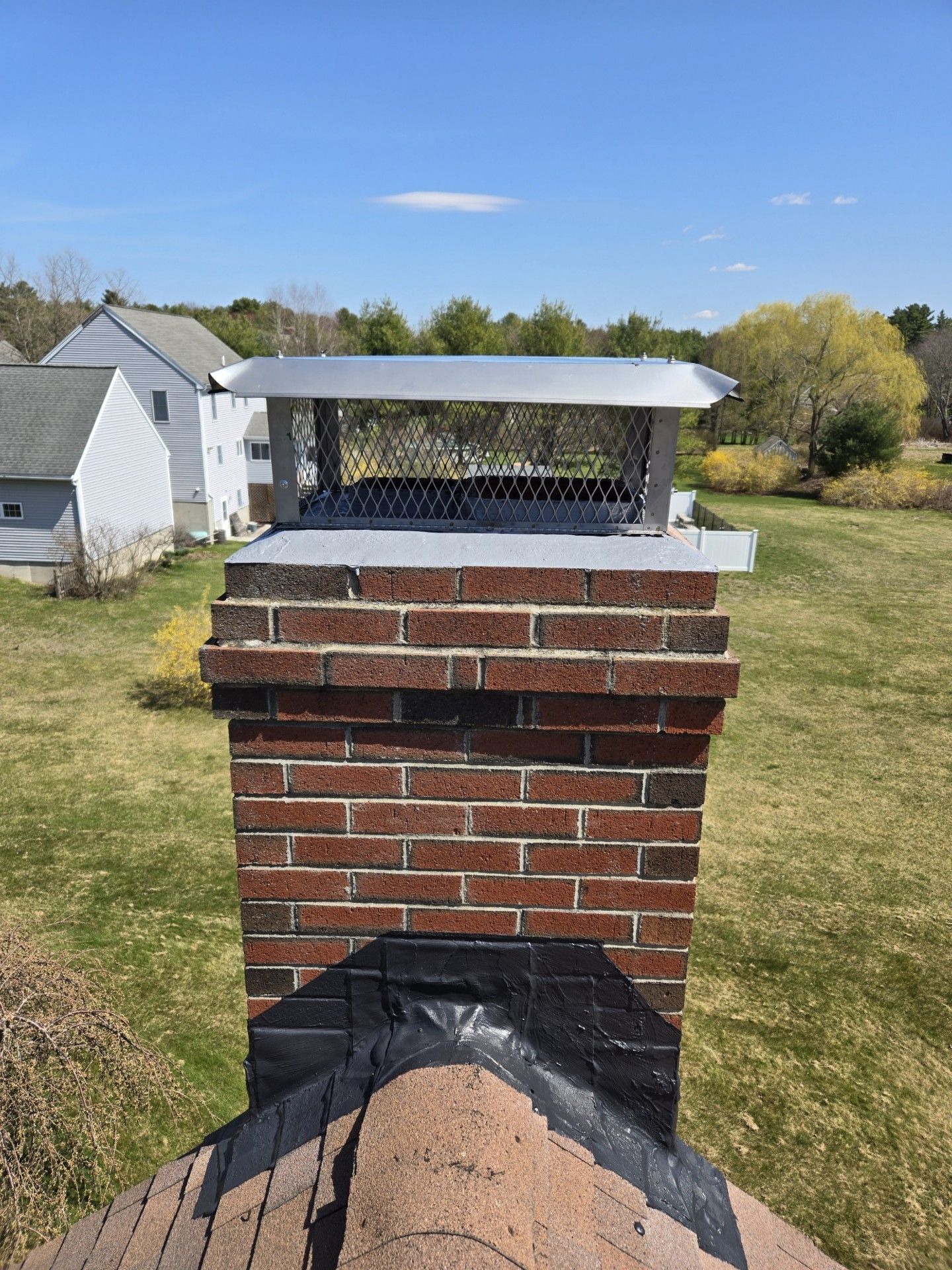 A brick chimney is sitting on top of a roof in a grassy field.