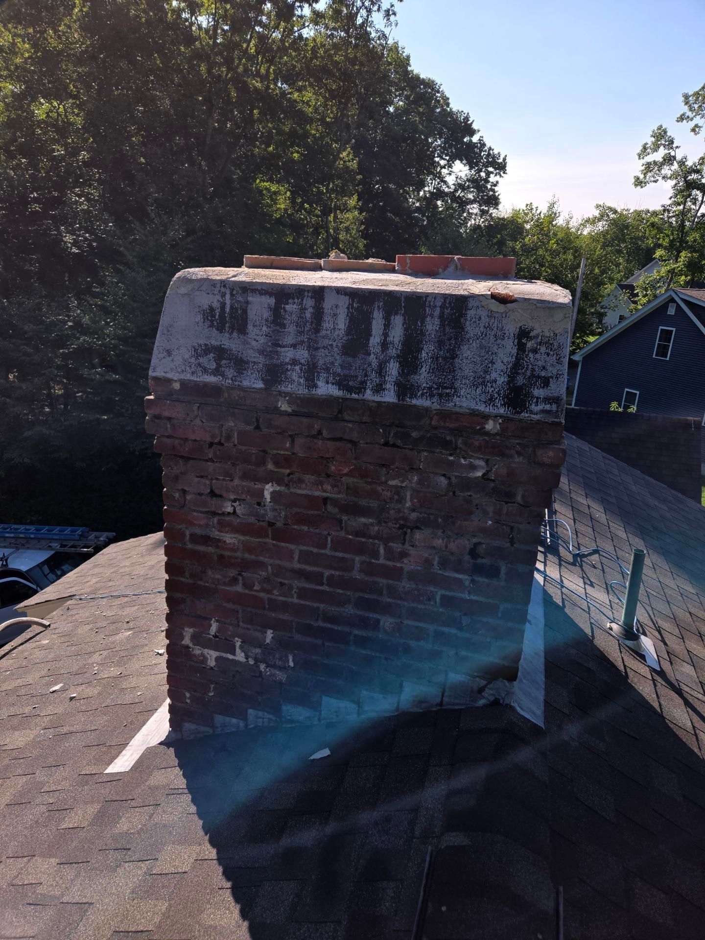 A brick chimney is sitting on top of a roof.