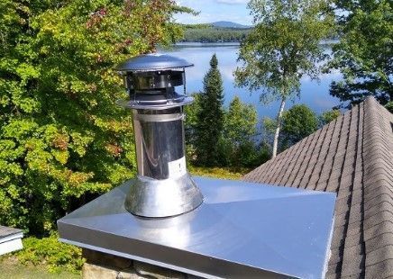 A stainless steel chimney on top of a roof overlooking a lake.