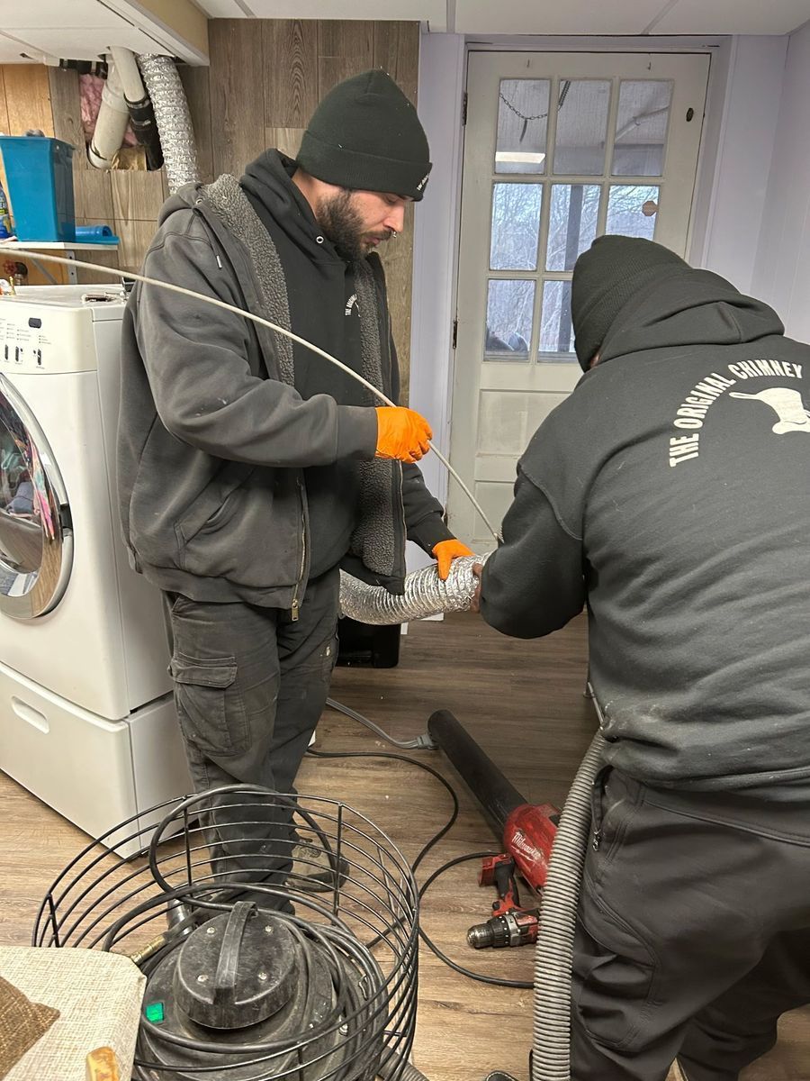 Two men are working on a drain in a laundry room.