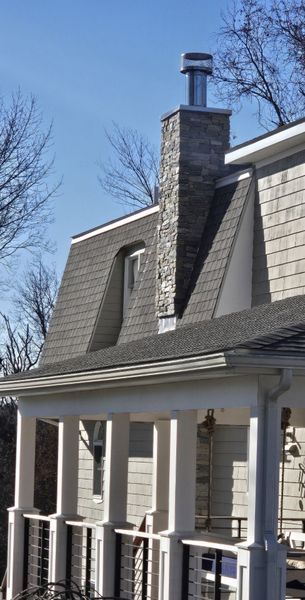 A house with a chimney on the roof and a porch.
