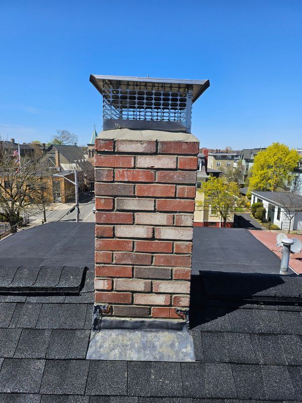 A brick chimney is sitting on top of a roof.