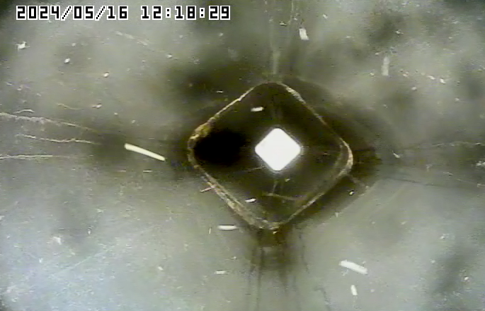 A camera is taking a picture of a hole in a pipe.