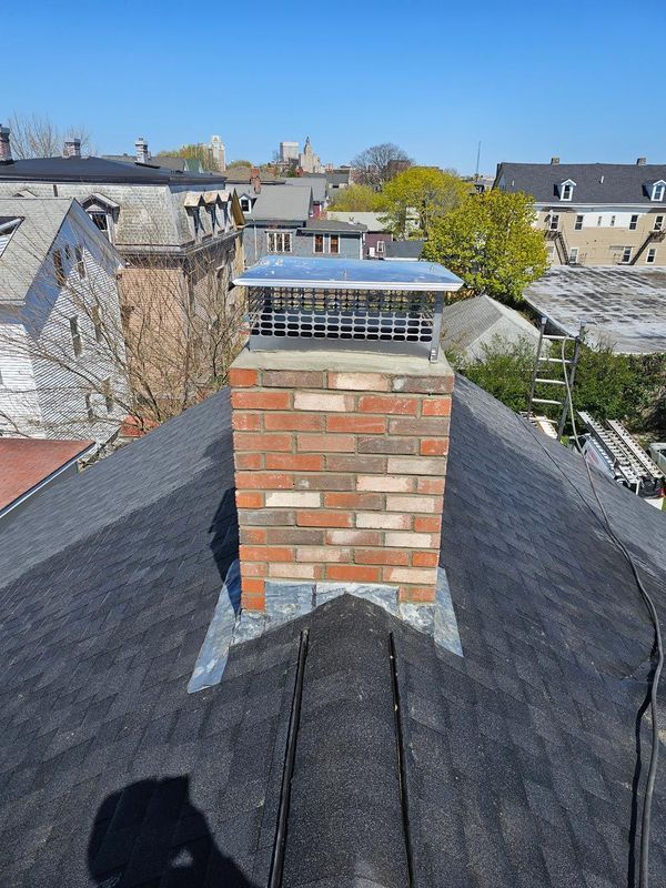 A brick chimney is sitting on top of a roof.