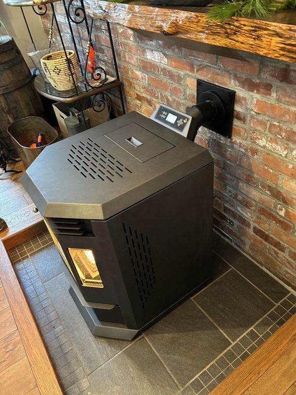 A black wood stove is sitting next to a brick fireplace.