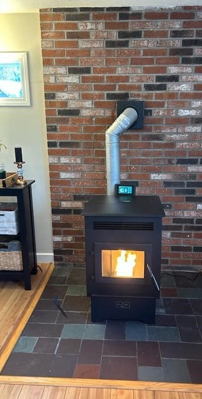 A wood stove is sitting in front of a brick wall in a living room.